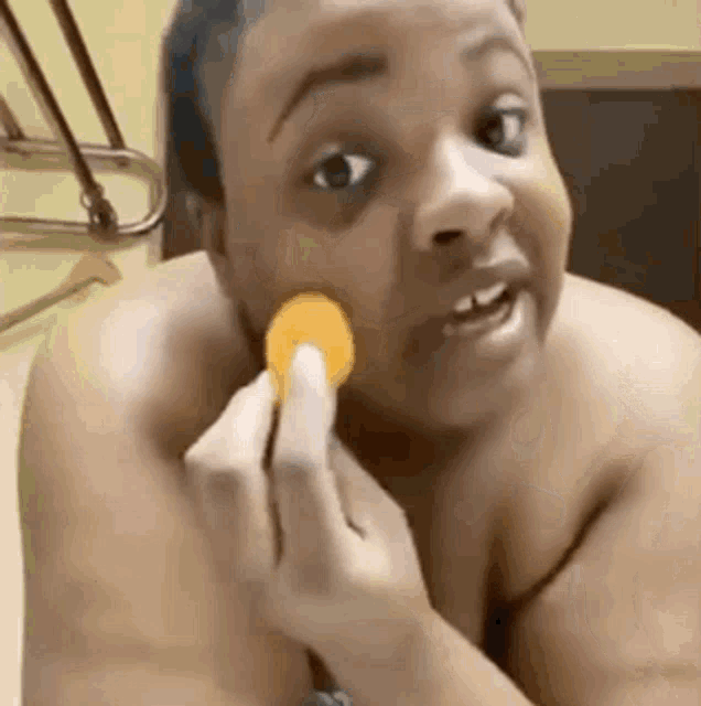 a shirtless woman is eating a potato chip .