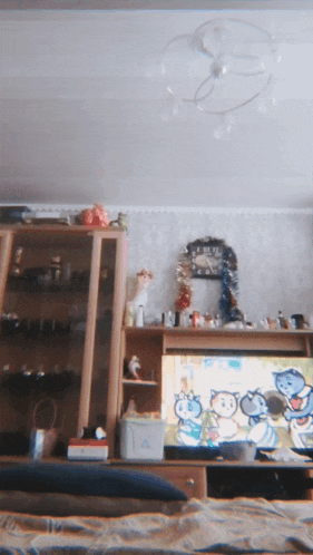 a living room with a clock on the wall and a television with cartoon cats on it