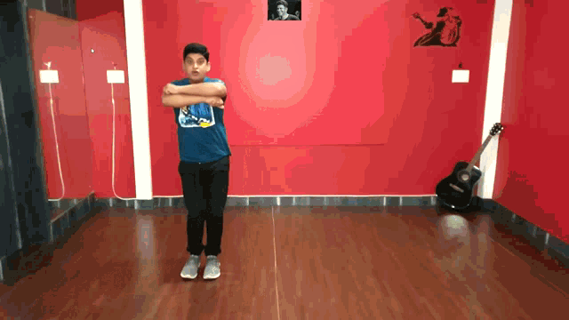 a boy in a blue shirt is standing in front of a guitar
