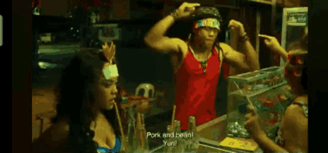 a man in a red tank top flexes his muscles in front of a woman who says pork and beans