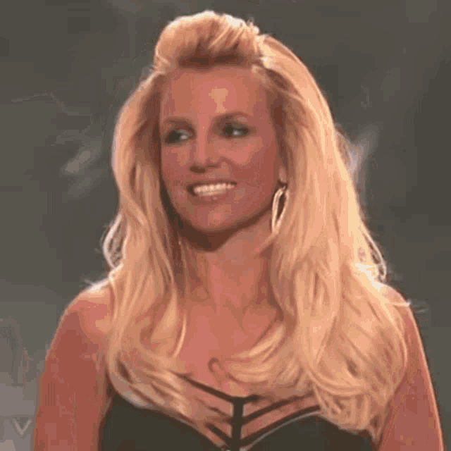 britney spears is smiling and wearing a black dress .