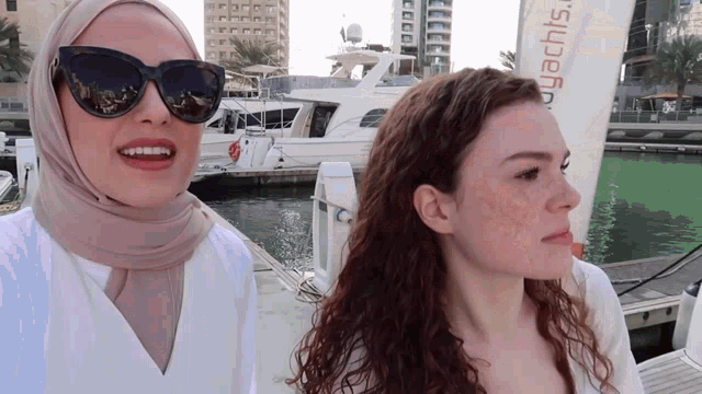 two women standing next to each other in front of a sign that says yachts