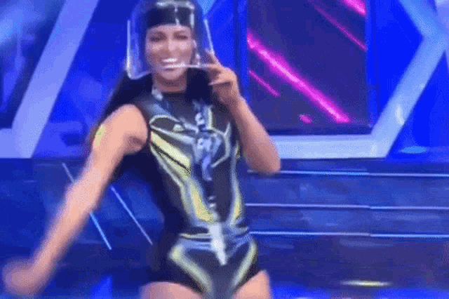 a woman in a superhero costume is dancing on a stage with a clear helmet on her head .