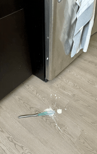 a spoon is laying on the floor next to a refrigerator