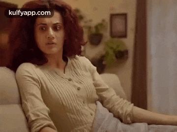 a woman is sitting on a couch in a living room looking at the camera .