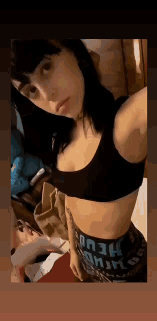 a woman is taking a selfie in a room while wearing a crop top and leggings .