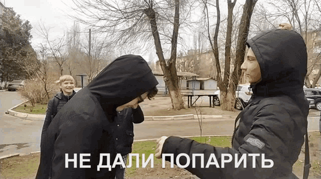 a man in a hooded jacket shakes hands with another man in a black jacket