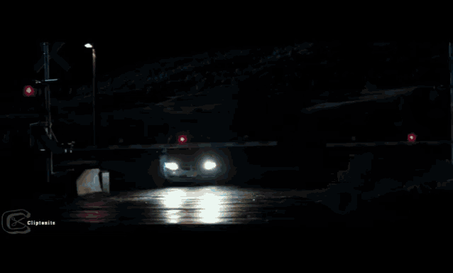 a white suv is driving through a railroad crossing at night