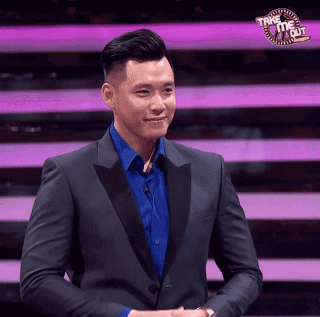 a man in a suit and blue shirt stands in front of a sign that says take me out