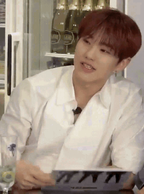 a young man with red hair is sitting in front of a refrigerator with bottles of champagne on it