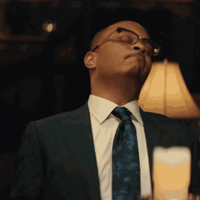 a man in a suit and tie is standing in front of a lamp with his eyes closed