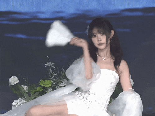 a woman in a white dress holding a fan