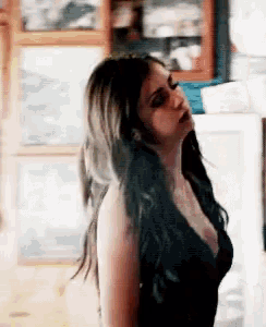 a woman in a black dress with a plunging neckline is standing in a room .
