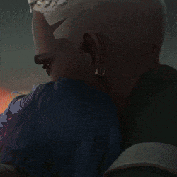a man with a shaved head is kissing another man in a blue shirt