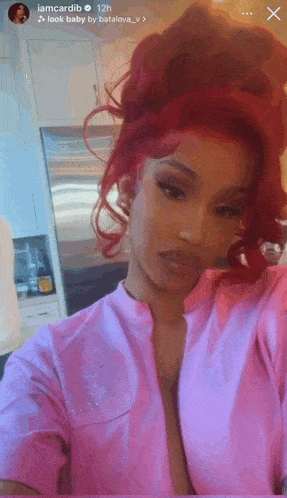 a woman with red hair is taking a selfie in a pink shirt .