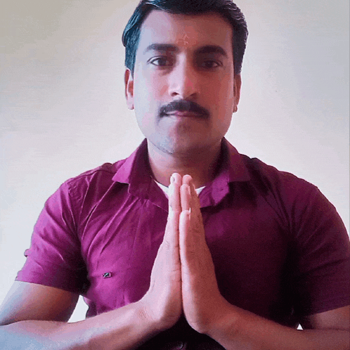 a man in a purple shirt with his hands folded