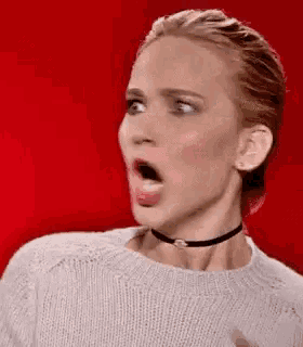 a woman wearing a choker and a sweater is sticking out her tongue .