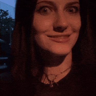 a close up of a woman 's face with a heart shaped necklace