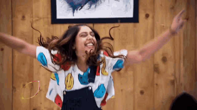 a woman with her arms outstretched is wearing a smiley face shirt