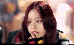 a young woman with red hair is holding her hand to her face .