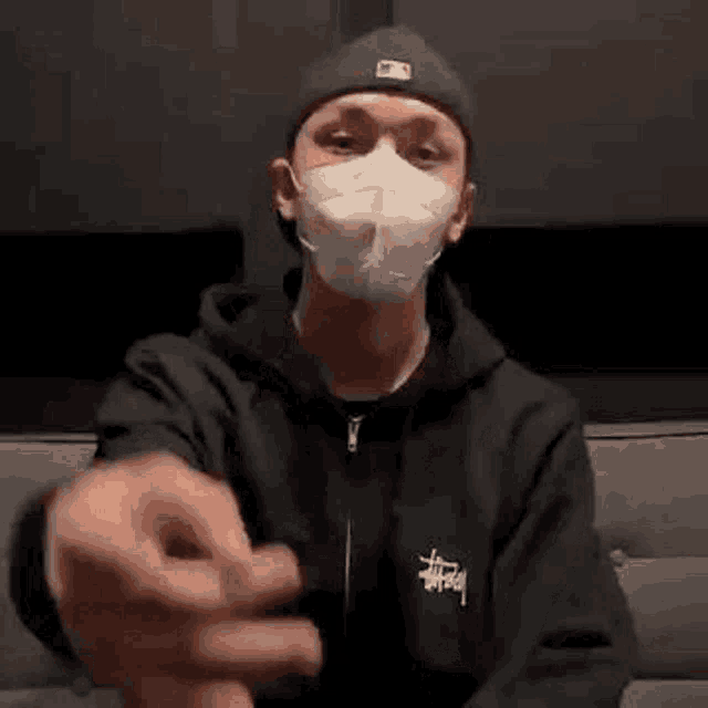 a man wearing a mask is sitting on a couch .