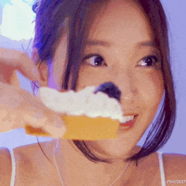 a close up of a woman holding a piece of cake with the word phatbod written on the bottom