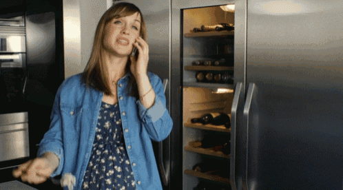 a woman talking on a cell phone in front of a refrigerator