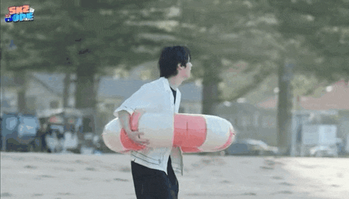 a man is walking on a beach holding a life preserver .