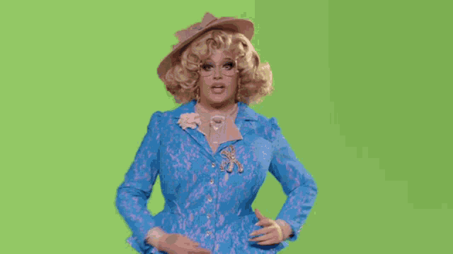 a drag queen is wearing a blue jacket and a pink hat .