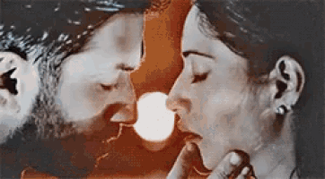 a man and a woman are kissing each other in front of a sun .