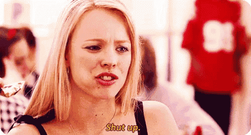 a woman is holding a piece of food in her hand and says `` shut up '' .