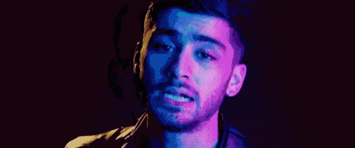 a close up of a man 's face with a beard in a dark room with blue lights .