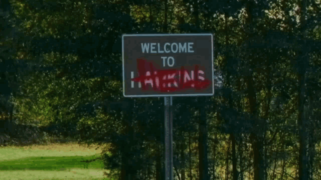 a sign that says welcome to hawkins is covered in red paint