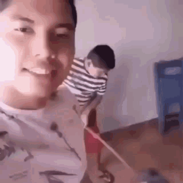 a man and a boy are standing next to each other in a room with a mop .