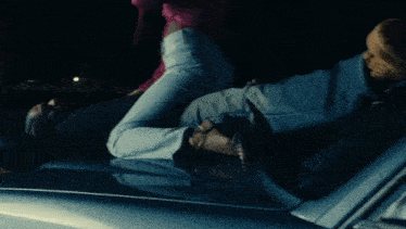 a woman in a pink top is sitting on the back of a man in a black shirt