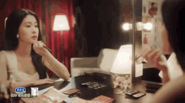 a woman is applying makeup in front of a mirror with a sticker that says ' x ' on it