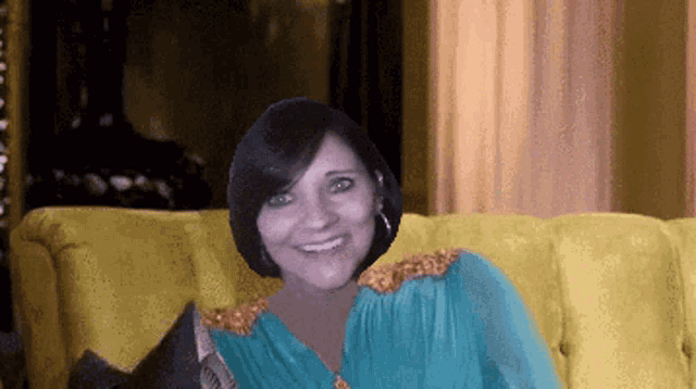 a woman is sitting on a yellow couch smiling