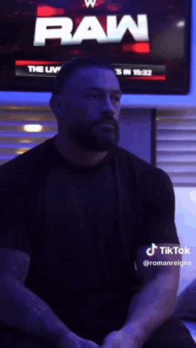 a man with a beard is sitting in front of a screen that says raw