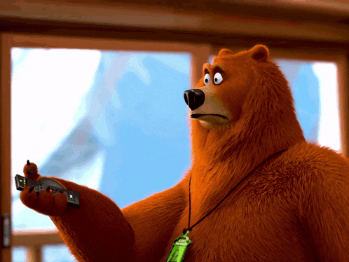 a brown bear with a green lanyard around his neck holds a remote control in his hand