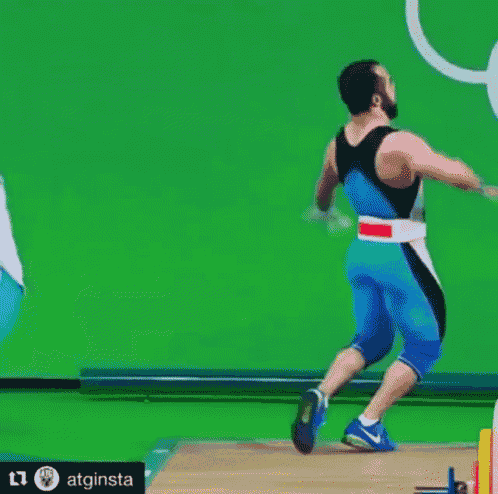 a man in a blue and black outfit is jumping in the air in front of a green background