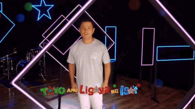 a man stands in front of a neon sign that says tayo ang liga ng isa