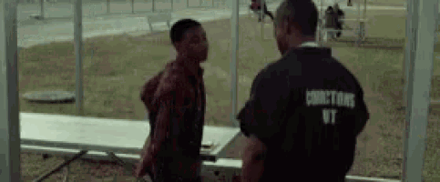 two men are standing next to each other in a prison yard . one of the men is wearing a shirt that says director .