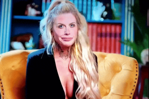 a woman with long blonde hair is sitting in a yellow chair and making a funny face