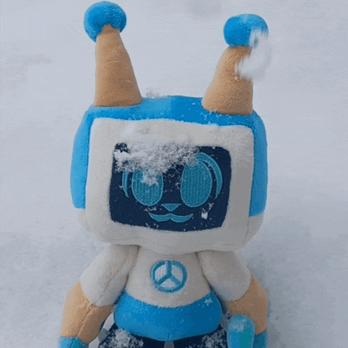 a stuffed animal with a peace sign on its chest is standing in the snow
