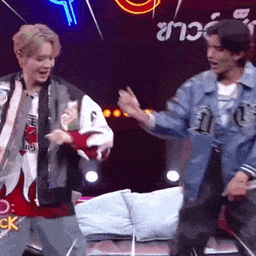two men are dancing on a stage in front of a neon sign that says ck
