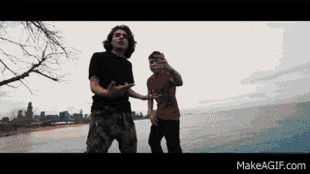 two men standing next to each other in front of a body of water with makeagif.com written on the bottom