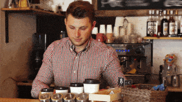 a man in a plaid shirt is behind a counter with a sign that says 8 05