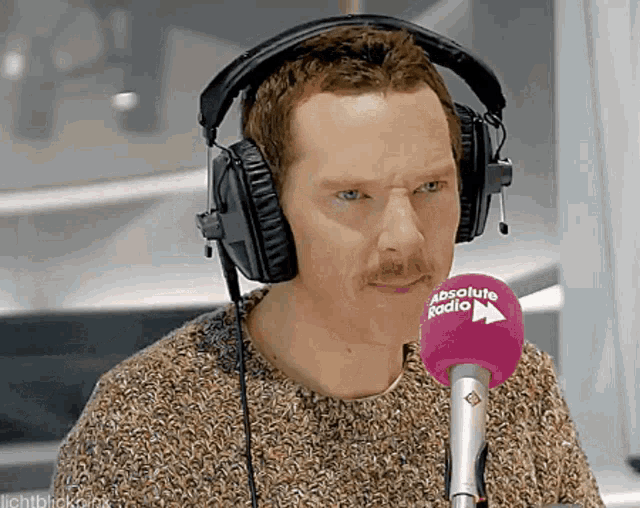 a man wearing headphones and a microphone that says absolute radio on it