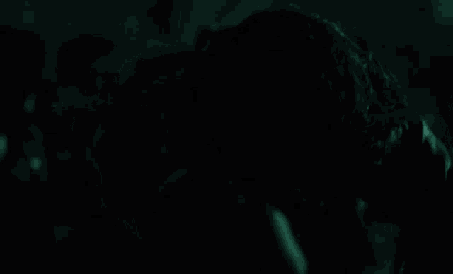 a man in a leather jacket is dancing in a dark room with a crowd of people .