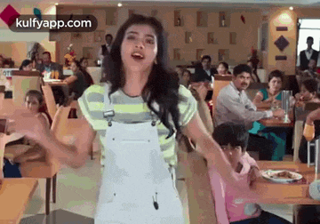 a woman is dancing in a restaurant while a group of people sit at tables .